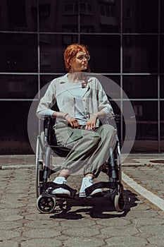 In front of a modern corporate building, a young woman sitting in a wheelchair confidently, symbolizing empowerment