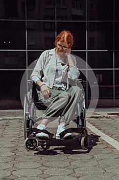 In front of a modern corporate building, a young woman sitting in a wheelchair confidently, symbolizing empowerment