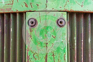 Front nose of farm equipment tractor. Metal background photo with rust, curvy metal vent and green chipping paint
