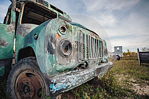 the front of the old abandoned bus is green in the field