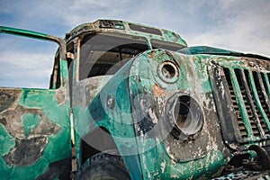 the front of the old abandoned bus is green in the field