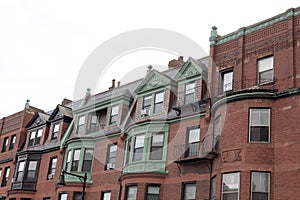 Front of old brownstone apartment buildings showing a variety of architectural styles and finishes