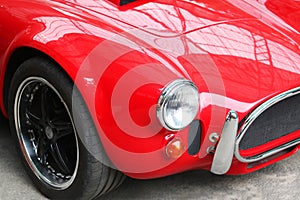 Front of old red car close up with round car headlight