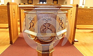 Front of old wooden baptism font in aisle of church on red carpet