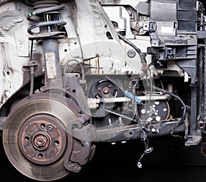 The front part of the car after an accident in a car repair service with a disassembled hood and metal grille and various parts in