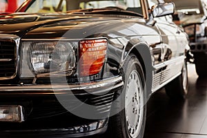 Front part of classical black automobile parked indoor at car show