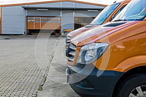 Front part of a row of two orange delivery vans in front of logi