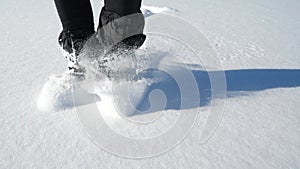 Front person view of legs in hockey skates boots moving in the deep snow. Snow blowing round  legs while moving on icy terrain.