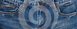 Front pockets, zipper, and its button of dark blue jeans. Close up shot. Clothing concept