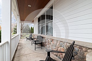 The front porch of a home with chairs sitting in front of the rock siding.