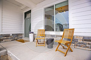 The front porch of a home with white exterior wall a and glass paned green door