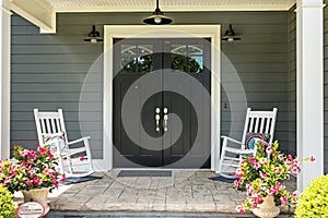 A front porch with two rocking chairs, stamped concrete floors, and double glass doors photo