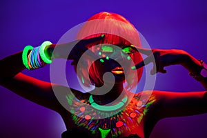 Front portrait of a woman with artistic colorful makeup and orange wig, with closed eyes, isolated violet background.