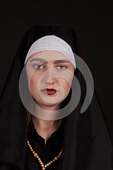 Front portrait of the young beautiful nun isoalted on black background.