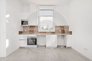 Front of a recently renovated kitchen with white wooden furniture, wooden countertop