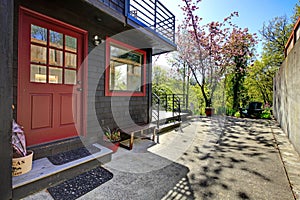 Front red door of black wood house with garden view.