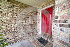 Front red door of a house with glass panel and bricks