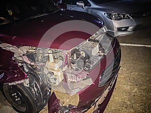 Front of red new car distorted by accident at night. Crashed new