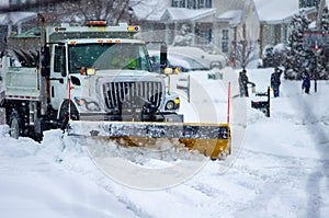 Front right view of city services snowplow truck clearing roadways of snow after winter storm covered streets in urban area