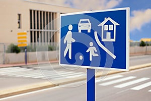 In front of a school. A blue sign indicates a game and sports street.