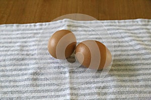 Front shot of 2 organic eggs on a white and gray dishtowel