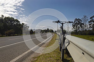 Front Shot to a black Mountain Bike clining to a safety highway metal fence in a sunny day photo