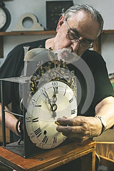 Front shot of a watchmaker repairing a large antique clock