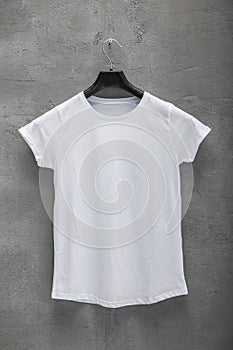 Front side of female white cotton t-shirt on a hanger