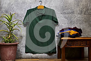 Front side of male green cotton t-shirt hanging on gray grunge marble wall