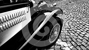 Front side part of vintage classic black hot rod car on a cobble road