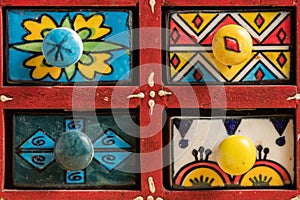 Front side of a small painted box with drawers for spices