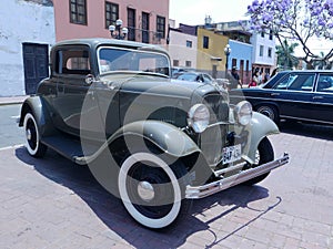 Front and side view of a green Ford De Luxe coupe two doors exhibited in Lima