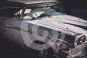 Front side view of a worn and beat up classic American car from the fifties