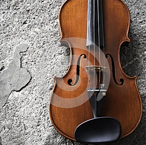 Front side of violin put at the right side of grunge surface cement ground floor