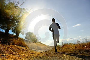 Front silhouette young sport man running cross country workout at summer sunset