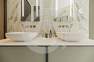 Front of a toilet with two twin sinks with frameless mirrors and gold