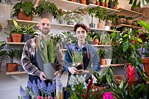 In front of tue camera in the floral store the sale assistant man and the florist lady have a conversation while