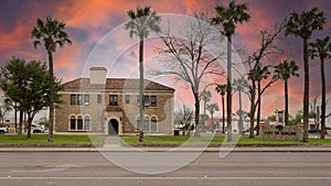 The front of Uvalde City Hall surrounded by Cabbage palm trees in downtown Uvalde, Texas.