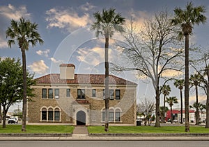 The front of Uvalde City Hall surrounded by Cabbage palm trees in downtown Uvalde, Texas.