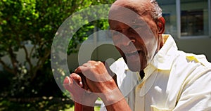 Front view of active Asian senior man sitting with walking stick in the garden of nursing home 4k