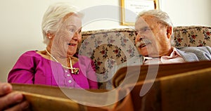 Front view of active Caucasian senior couple looking at photo album in nursing home 4k