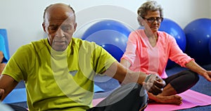 Front view of active mixed-race senior people performing yoga in fitness studio 4k