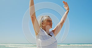 Front view of active senior Caucasian woman performing yoga on the beach 4k