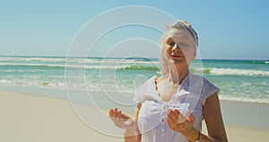 Front view of active senior Caucasian woman performing yoga on the beach 4k