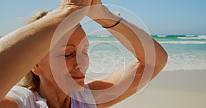 Front view of active senior Caucasian woman performing yoga on the beach 4k