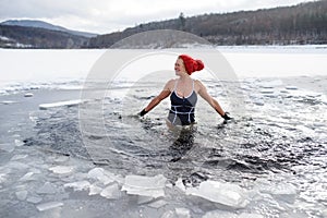 Front view of active senior woman in swimsuit outdoors in winter, cold therapy concept.