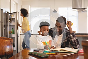 African American father helping his son with homework at table