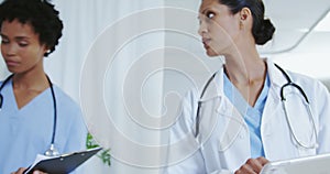 Front view of African american female doctors attaching iv drip on male patient hand in the ward