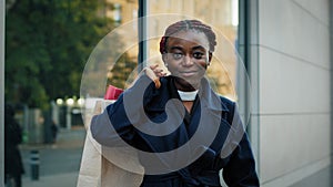 Front view african american girl shopper shopaholic consumer standing on city street near building after shopping with