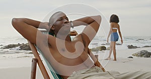 Front view of African american man relaxing with eyes closed on the beach 4k